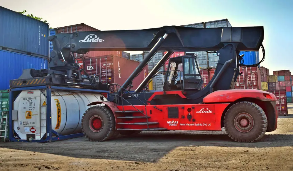 Reach stacker lifting a tank container at a container yard, cargo handling in Surabaya
